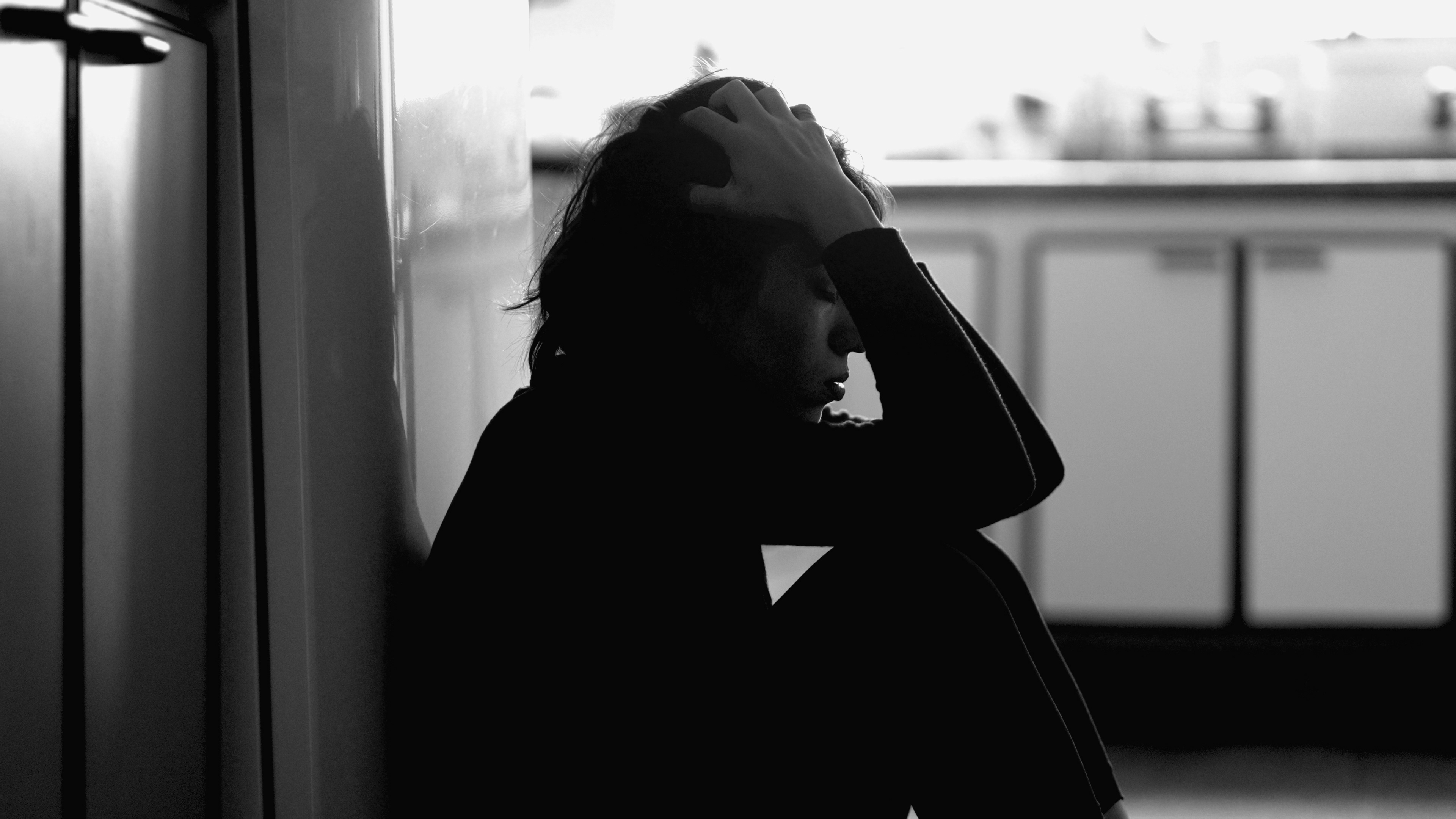 жінка сидить, тримає голову, пригнічена